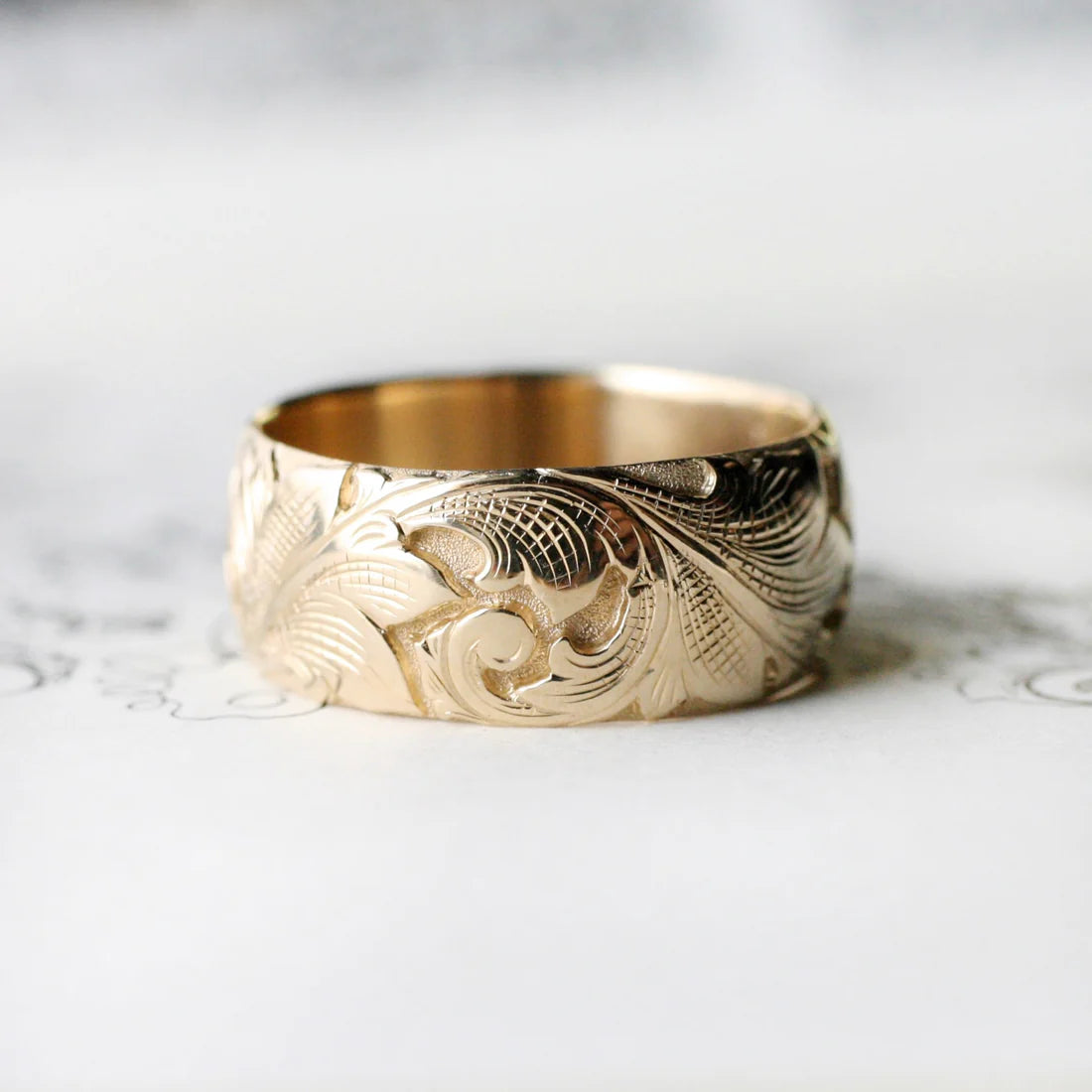 14k gold wide acanthus band on decorative background – hand-engraved scroll and leaf detail.