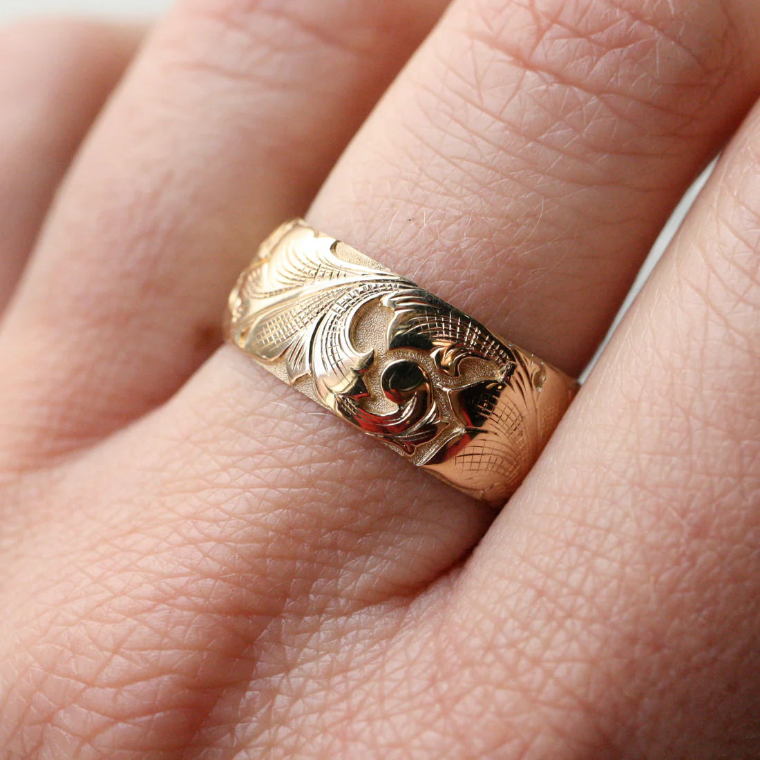 Wide 14k gold acanthus engraved band worn on finger – deep relief scroll motif.