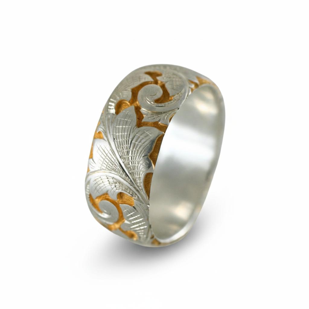 Wide two-tone acanthus engraved band in silver and gold shown at an angled view on white background.