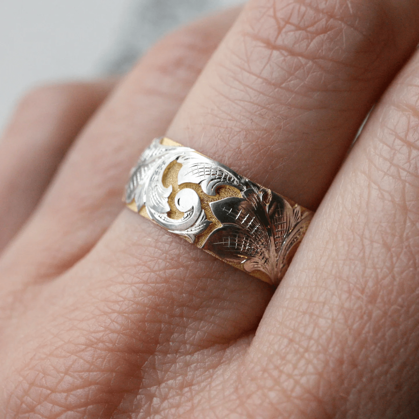 Two-tone wide acanthus band worn on finger – detailed hand-engraved scrollwork.