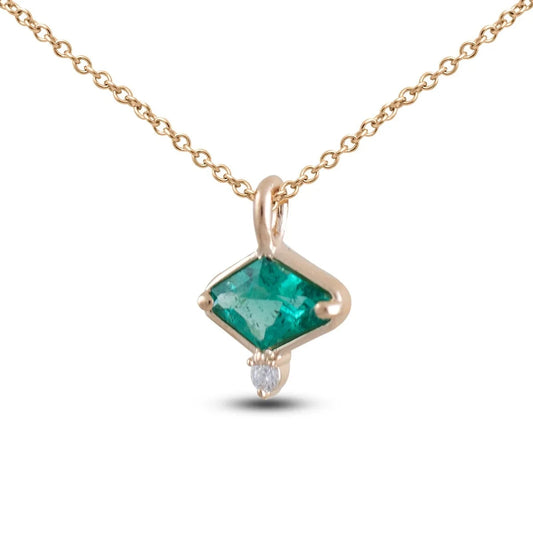 Emerald and White Diamond Necklace by Michaela Farkasovska featuring a natural green Zambian emerald in a 14k yellow gold bezel with a small white diamond accent.